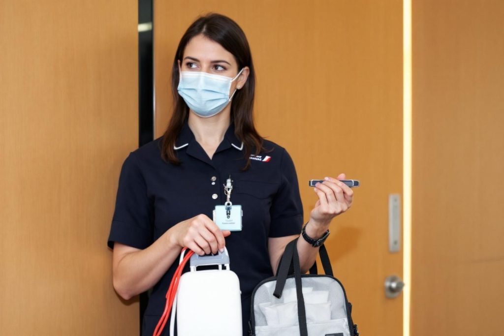 Femme en uniforme noir portant un masque médical et des sacs