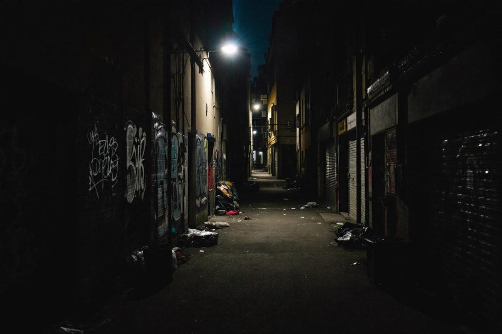 Passage étroit la nuit avec des graffitis et des détritus