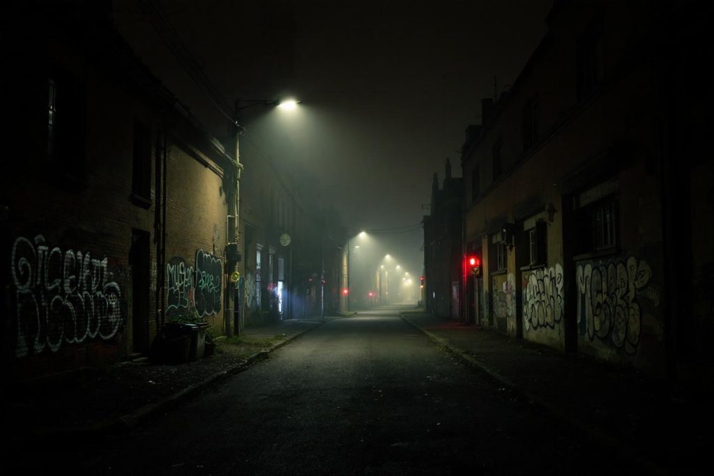 Rue urbaine déserte la nuit, éclairée par des lampadaires