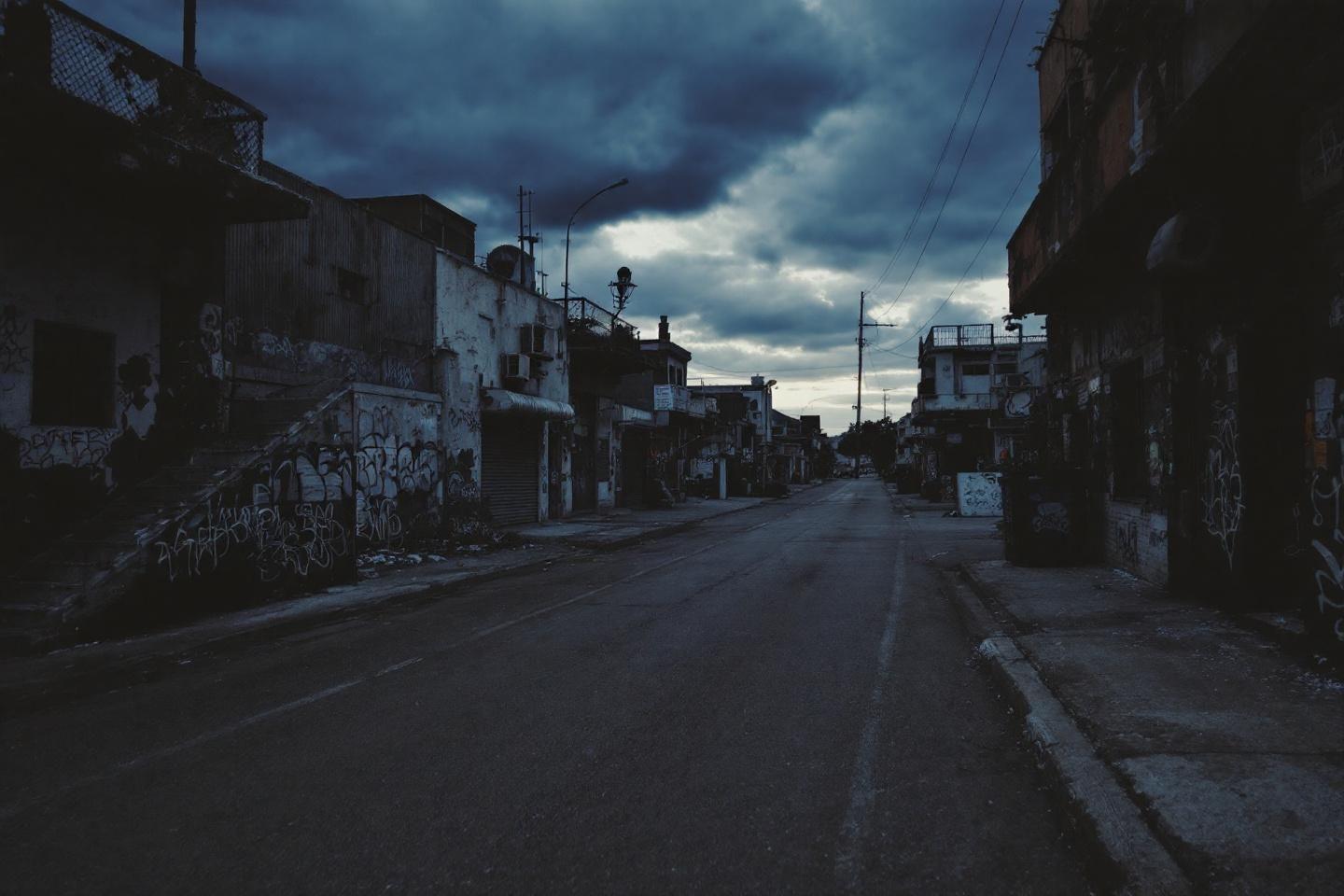 Rue abandonnée entre bâtiments délabrés sous ciel nuageux
