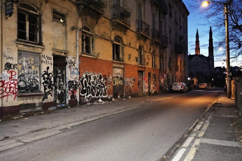 Façades graffeuses, rue déserte, clocher en arrière-plan
