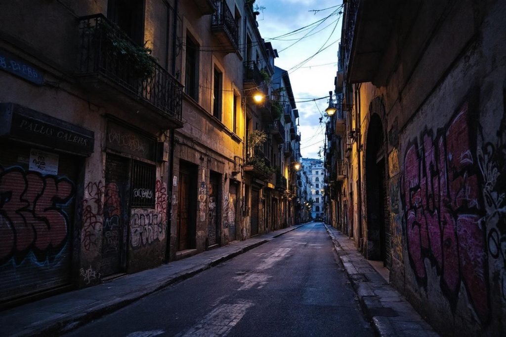 Rue étroite avec graffitis, éclairée par des lampadaires