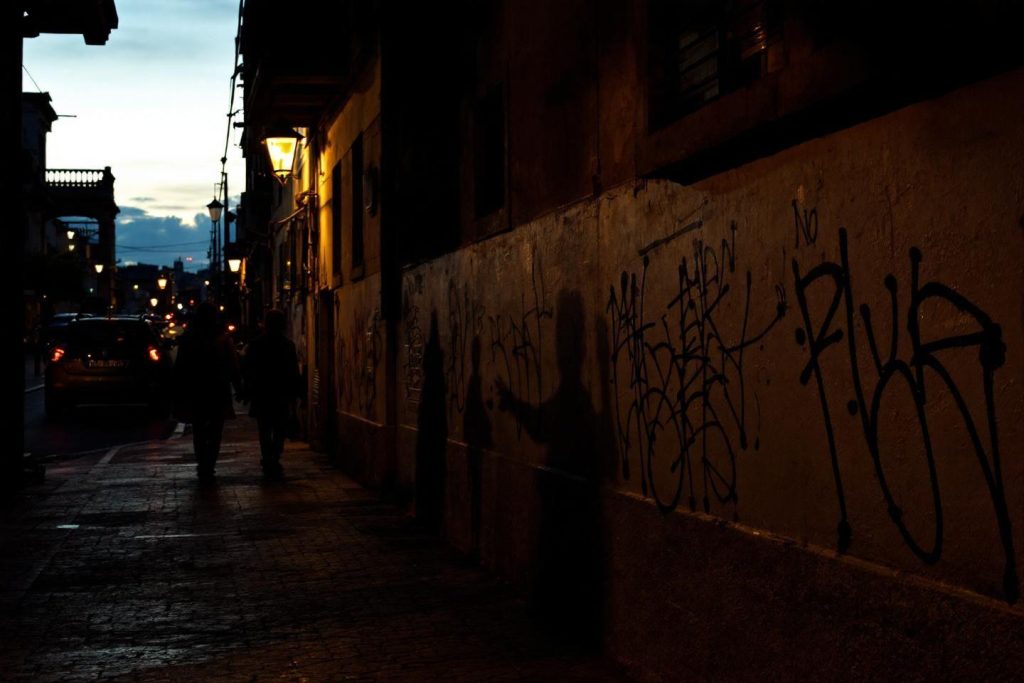 Rue urbaine la nuit avec lampadaires et murs tagués