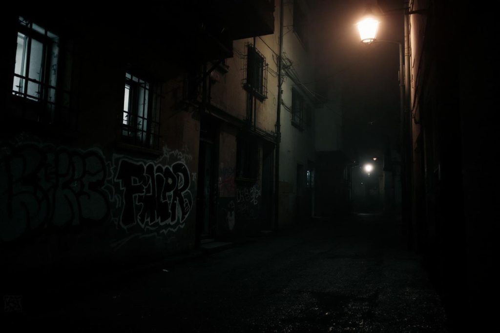 Passage étroit la nuit avec graffitis et lumière diffuse