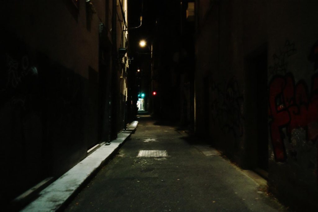 Passage étroit obscur éclairé par un réverbère distant